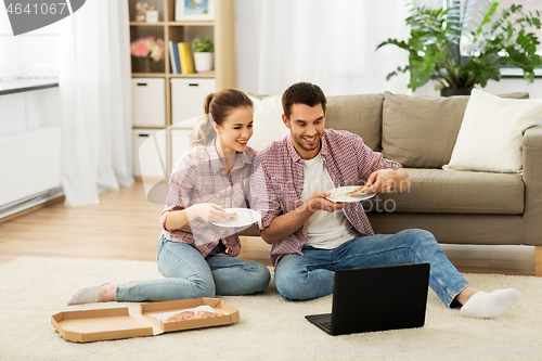 Image of happy couple with laptop eating pizza at home