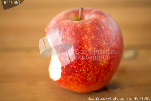 Image of ripe red bitten apple on wooden table