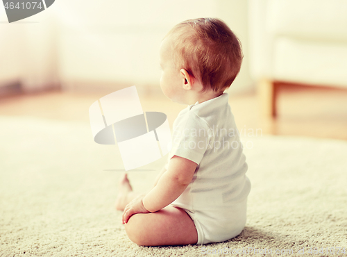 Image of happy baby boy or girl sitting on floor at home