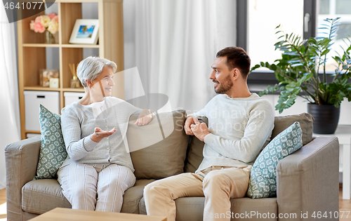 Image of senior mother talking to adult son at home