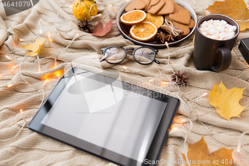 Image of tablet computer, hot chocolate and autumn leaves
