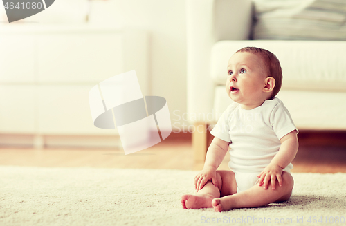 Image of happy baby boy or girl sitting on floor at home