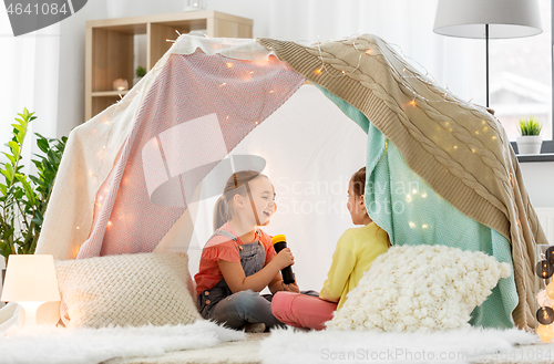 Image of girls playing with torch in kids tent at home