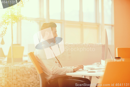 Image of relaxed young businessman first at workplace at early morning