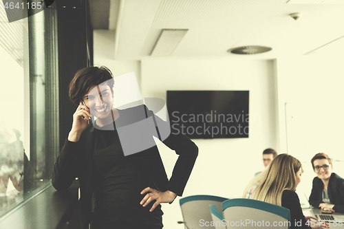 Image of Elegant Woman Using Mobile Phone by window in office building