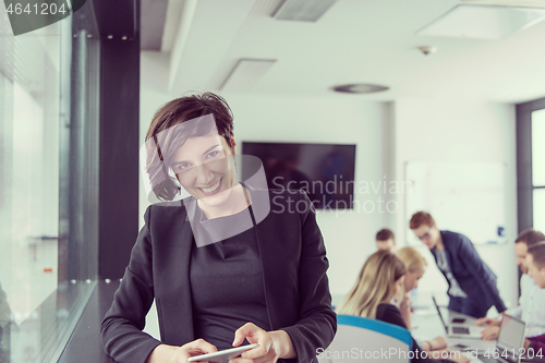 Image of Elegant Woman Using Mobile Phone by window in office building