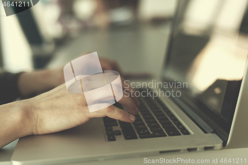 Image of close up of business womans hand typing on laptop with team on m