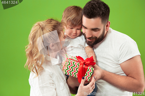 Image of happy family with kid together and smiling at camera isolated on green