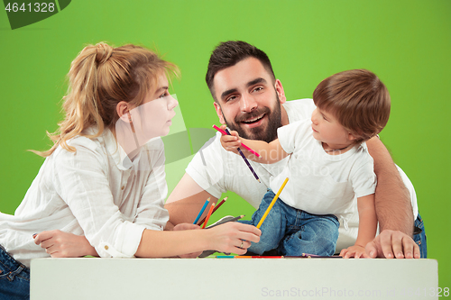 Image of happy family with kid together and smiling at camera isolated on green