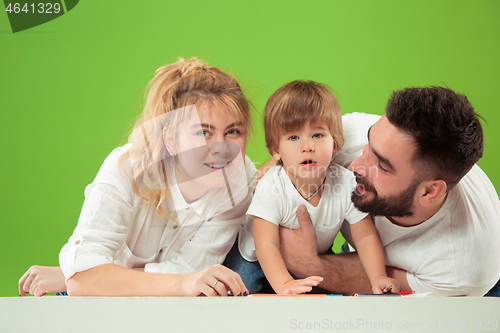 Image of happy family with kid together and smiling at camera isolated on green