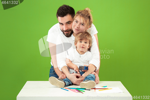 Image of happy family with kid together and smiling at camera isolated on green