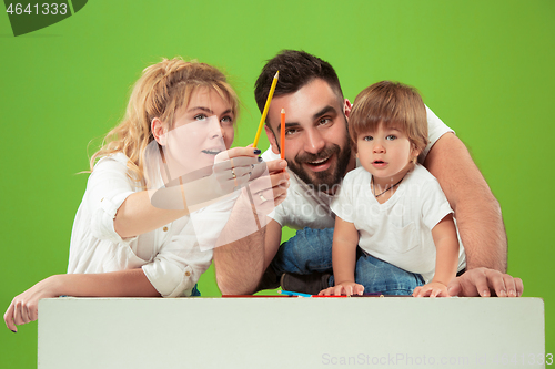 Image of happy family with kid together and smiling at camera isolated on green