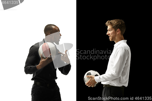 Image of Portrait of a smiling men holding soccer and basketball ball isolated on a white and black background