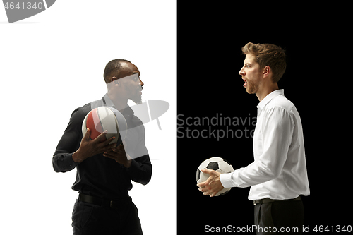 Image of Portrait of a smiling men holding soccer and basketball ball isolated on a white and black background