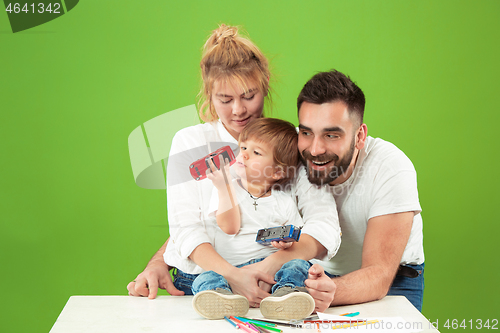 Image of happy family with kid together and smiling at camera isolated on green