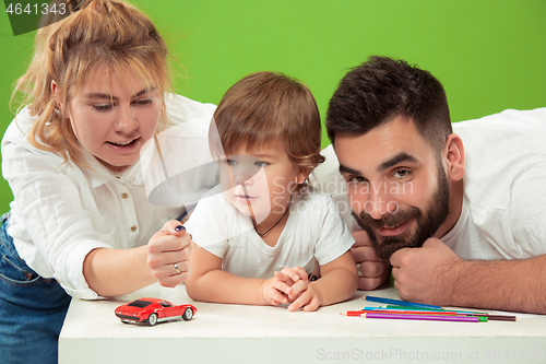 Image of happy family with kid together and smiling at camera isolated on green