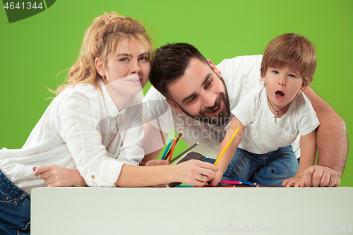 Image of happy family with kid together and smiling at camera isolated on green