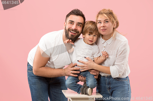Image of happy family with kid together and smiling at camera isolated on pink