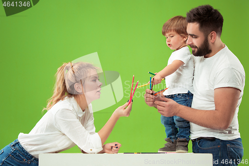 Image of happy family with kid together and smiling at camera isolated on green