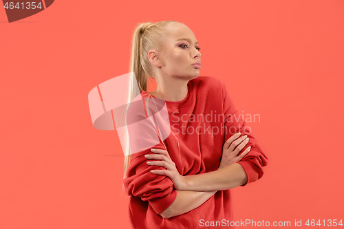 Image of The serious business woman standing and looking at camera against coral background.