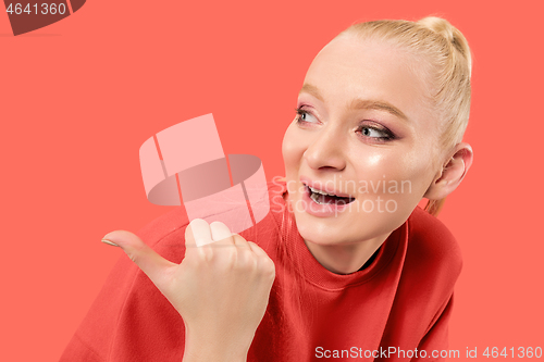 Image of Beautiful woman looking suprised isolated on coral