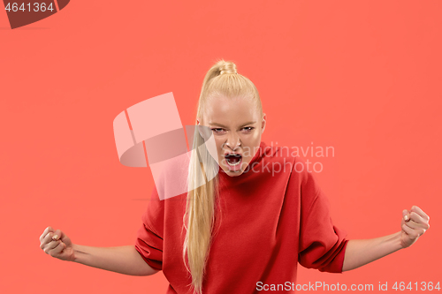 Image of The young emotional angry woman screaming on coral studio background