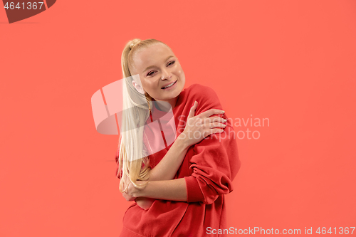 Image of The happy business woman standing and smiling against coral background.