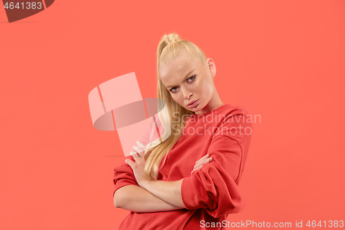 Image of The serious business woman standing and looking at camera against coral background.