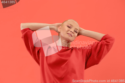 Image of The happy business woman standing and smiling against coral background.