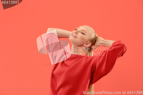 Image of The happy business woman standing and smiling against coral background.