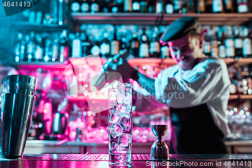 Image of Expert barman is making cocktail at night club.