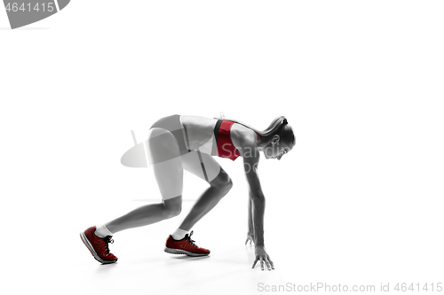 Image of Portrait of young sporty woman at starting block of race isolated over white background