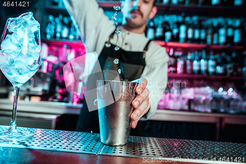 Image of Expert barman is making cocktail at night club.