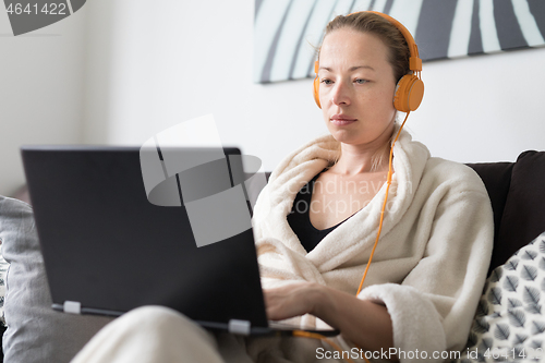 Image of Stay at home and social distancing. Woman in her casual home bathrobe working remotly from her living room. Video chatting using social media with friend, family, business clients or partners