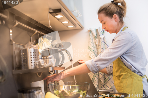 Image of Stay at home housewife woman cooking in kitchen, stir frying dish in a saucepan, preparing food for family dinner.