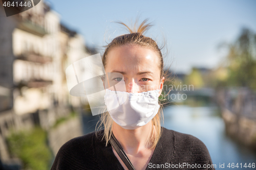 Image of COVID-19 pandemic coronavirus. Young girl in city street wearing face mask protective for spreading of coronavirus disease 2020. Close up of young woman with medical mask on face against SARS-CoV-2