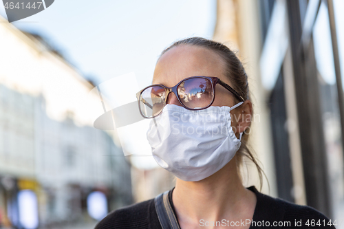 Image of COVID-19 Pandemic Coronavirus. Young girl in city street wearing face mask protective for spreading of Coronavirus Disease 2019. Close up of young woman with medical mask on face against SARS-CoV-2