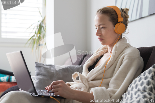 Image of Stay at home and social distancing. Woman in her casual home bathrobe working remotly from her living room. Video chatting using social media with friend, family, business clients or partners