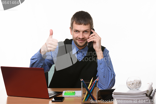 Image of Manager talks on the phone with his thumb up