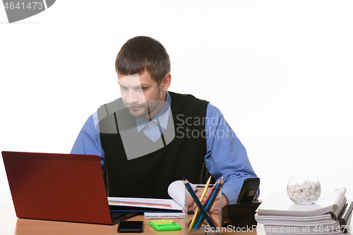 Image of man looks at the monitor of the laptop sitting at a desk