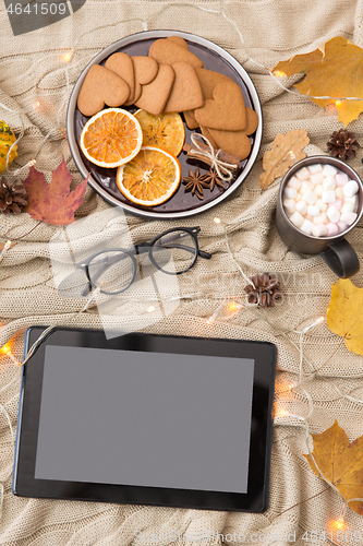 Image of tablet computer, hot chocolate and autumn leaves