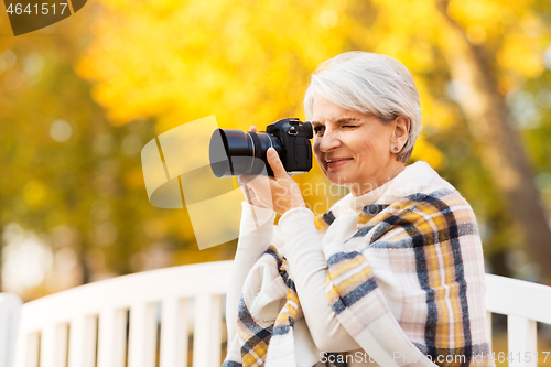 Image of senior woman with photo camera at autumn park