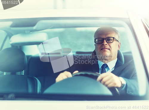 Image of happy senior businessman driving car