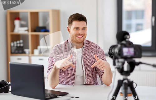 Image of male blogger with camera videoblogging at home