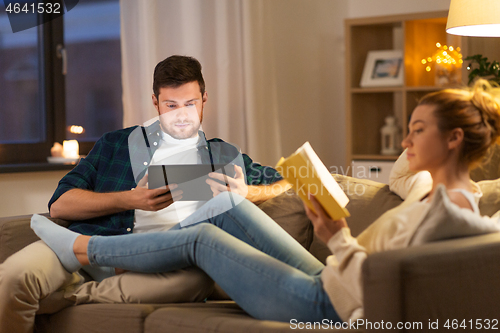 Image of couple with tablet computer and book at home