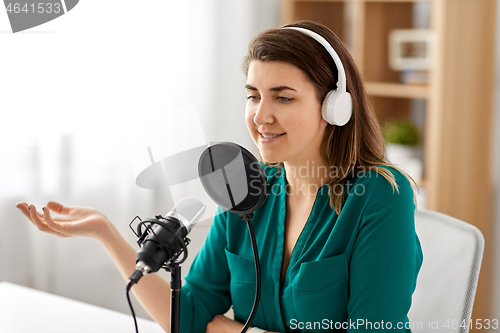 Image of woman with microphone recording podcast at studio