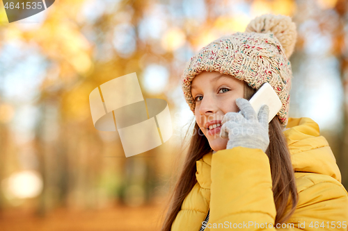 Image of happy girl calling on smartphone at autumn park