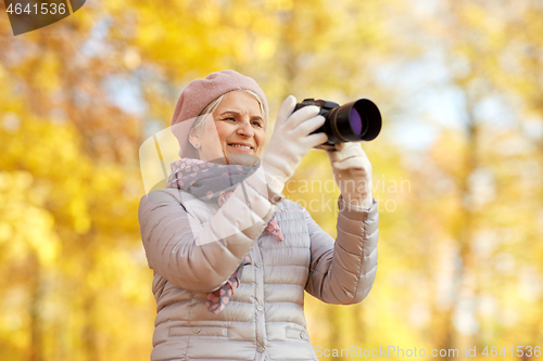 Image of senior woman with photo camera at autumn park