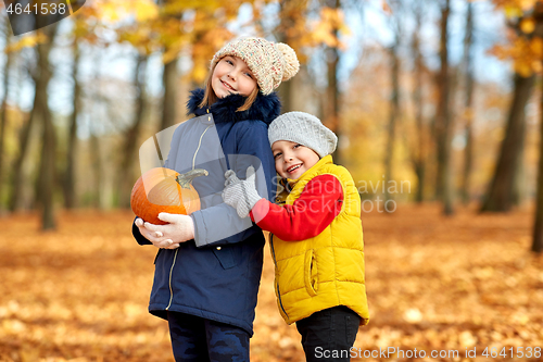 Image of happy children with pumpkin hugging at autumn park