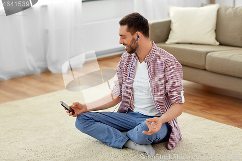 Image of man in earphones listening to music and meditating